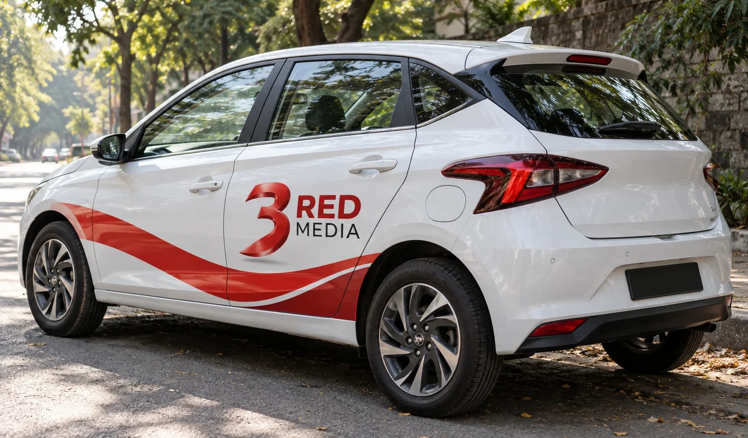 White hatchback with a partial vinyl wrap carrying the 3 Red Media logo, Pune street