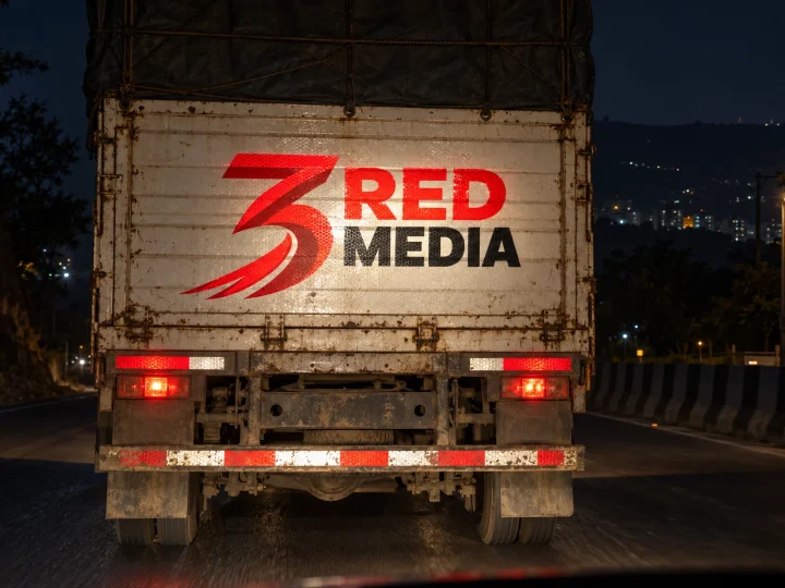 Reflective vinyl stickers on the back of a truck with the 3 Red Media logo, glowing in headlights