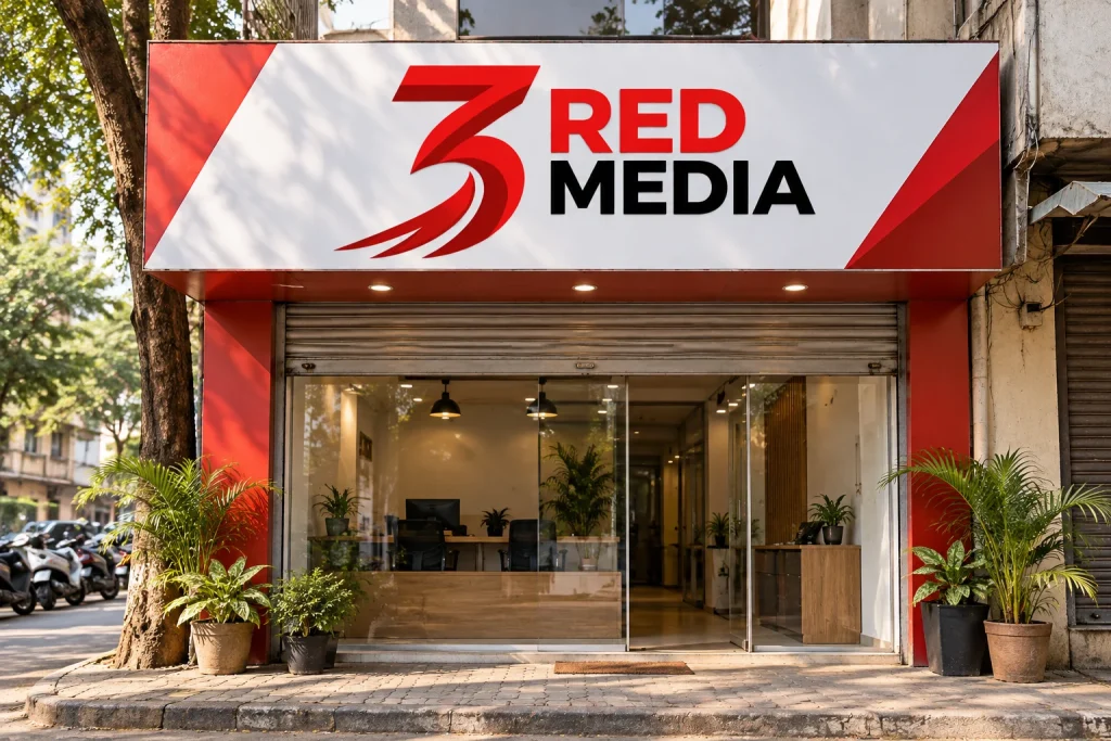 Small shop front with a wide fascia board in printed vinyl carrying the 3 Red Media logo above the shutter, the board that sits over the glass in a Sus row