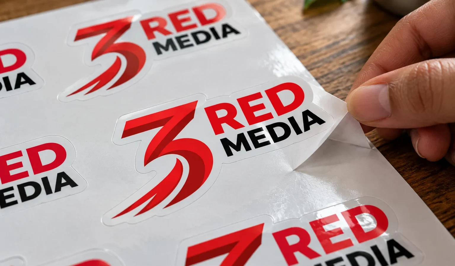 Die-cut vinyl stickers of the 3 Red Media logo on a sheet, one being peeled off